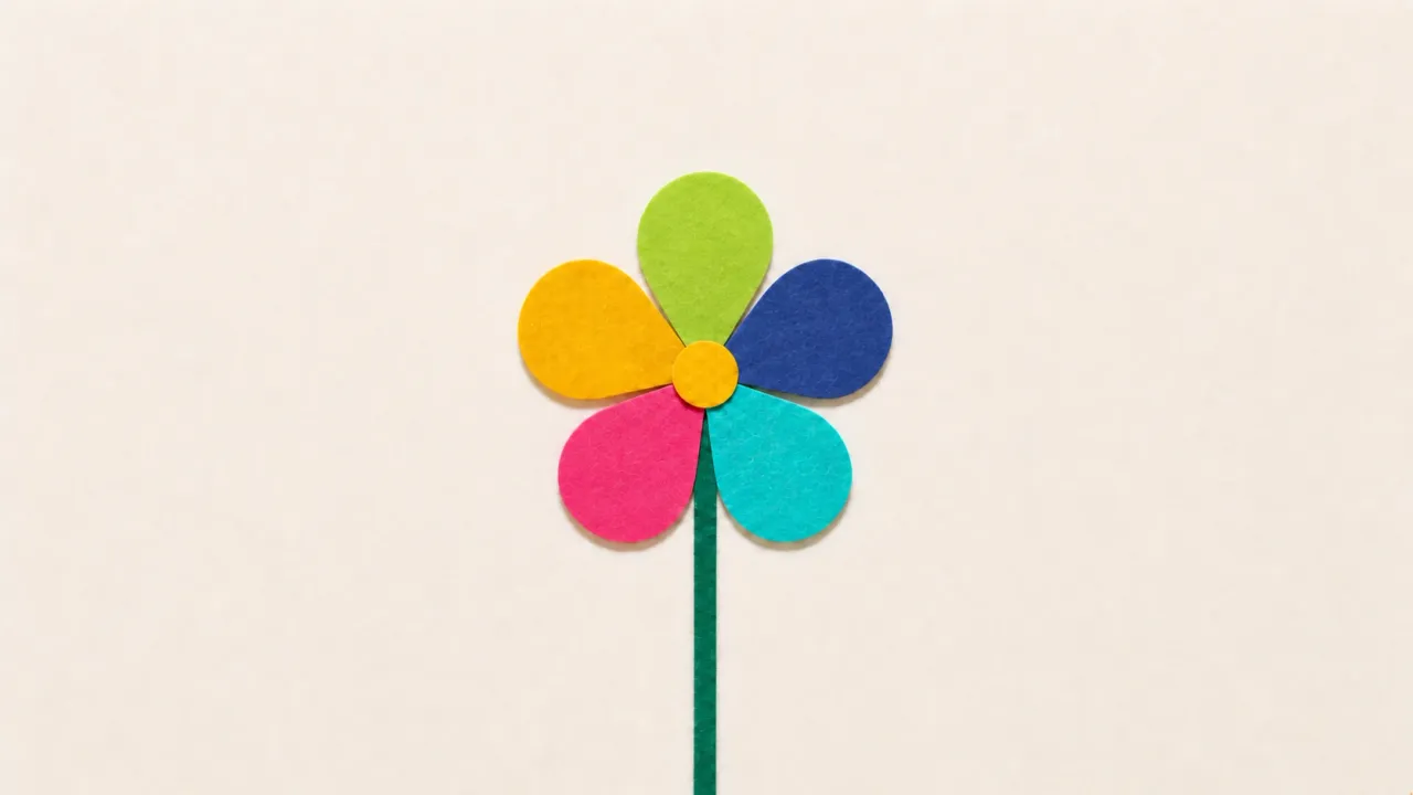 A paper flower with five petals in green, blue, teal, pink and yellow around a yellow centre, on a green stem against a pale paper background