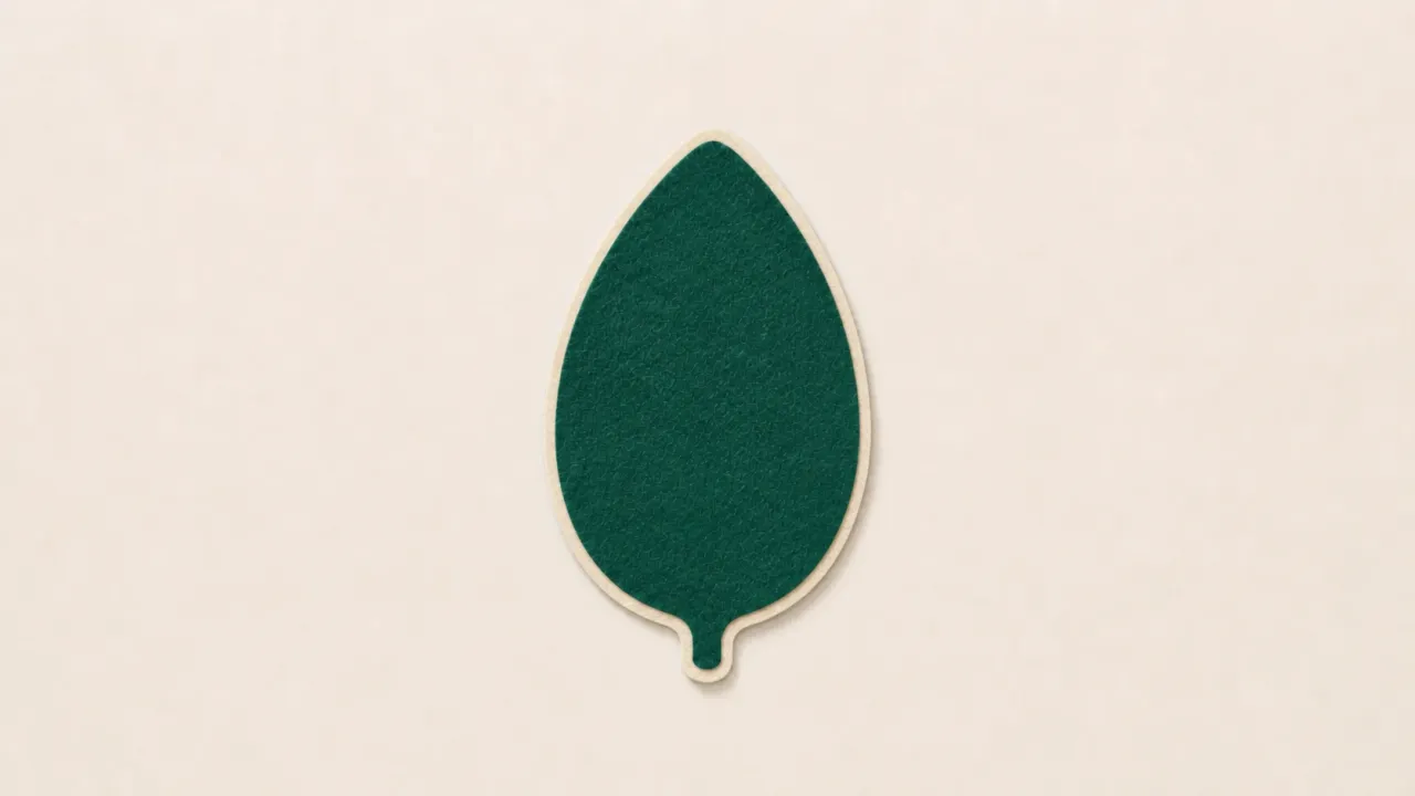 A dark green paper MongoDB leaf split by a narrow slit down its middle on a pale paper background